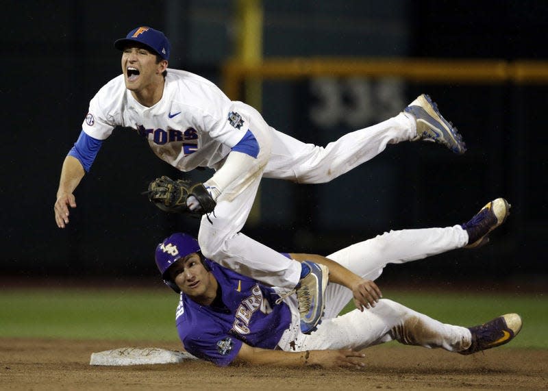 Florida shortstop Dalton Guthrie, top, falls after being hit by LSU’s Jake Slaughter at second base on a double play hit by Michael Papierski during Game 2 of the College World Series baseball finals in Omaha, Neb., Tuesday. Papierski was out at first. AP Photo/NATI HARNIK