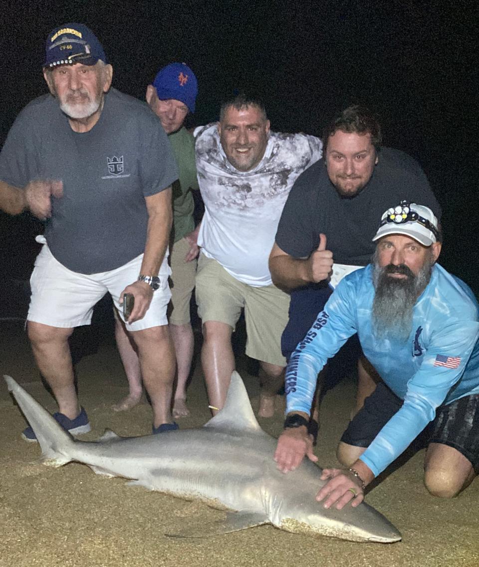 Dustin Smith (right) of NSB Shark Hunters, helped these visitors from The Villages bring a 65-inch blacktip to the beach for a quick photo-op before release.