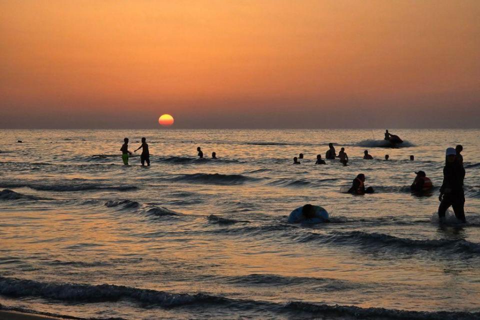 People swim in the sea at sunset in Qarabuli, Libya - Saturday, July 20, 2024