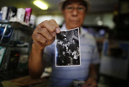 Resident Kohei Jinno, 79, shows a photograph of himself (2nd L wearing suit) taken on January 2, 1957 in front of his previous home, at his shop inside Kasumigaoka apartment complex which is located near the National Olympic Stadium in Tokyo September 18, 2013. REUTERS/Issei Kato