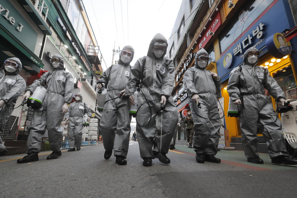 South Korean army soldiers wearing protective gears spray disinfectant as a precaution against the new coronavirus at a shopping street in Seoul, South Korea, Wednesday, March 4, 2020. The coronavirus epidemic shifted increasingly westward toward the Middle East, Europe and the United States on Tuesday, with governments taking emergency steps to ease shortages of masks and other supplies for front-line doctors and nurses. (AP Photo/Ahn Young-joon)