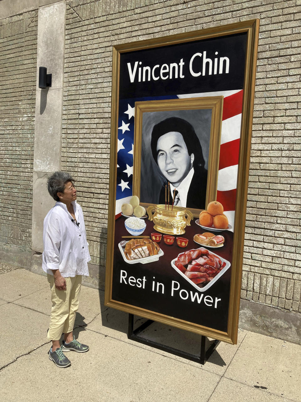 Activist and author Helen Zia poses Thursday, June 15, 2022, next to a painting of Vincent Chin in Detroit. The city is partnering with The Vincent Chin 40th Remembrance & Rededication Coalition to honor civil rights efforts that began with Chin's 1982 slaying. Chin, a Chinese American, was beaten to death in Detroit by two white men who never served jail time. The commemoration comes as hate crimes against Asian Americans are on the rise in the U.S. (AP Photo/Corey Williams)