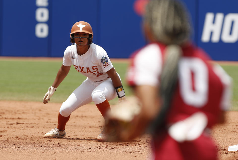 Texas' Alyssa Washington, left, watches Oklahoma's Rylie Boone (0) during the first inning of an NCAA softball Women's College World Series game on Saturday, June 4, 2022, in Oklahoma City. (AP Photo/Alonzo Adams)