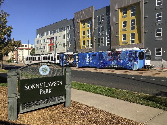 In this Sept. 17, 2016 photo, a sign identifying Sonny Lawson Park sits while a commuter rail passes in Denver's Five Points neighborhood. The historic black neighborhood was once called "The Harlem of West," a place where Billie Holiday, Count Basie and Miles Davis performed and novelist Jack Kerouac tried to capture the spirit of the bebop movement in "On The Road." (AP Photo/Russell Contreras)