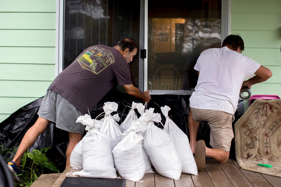 Tony Pagan, left, helps a friend set sandbags in place over a plastic tarp on the back door as they prepare to evacuate before Hurricane Dorian arrives with its storm surge and tropical storm winds, Wednesday, Sept. 4, 2019, in Tybee Island, Ga. “This is climate change, though President Trump denies that it is,” Pagan, a 69-year-old retired electrician said as he and his wife finished packing to evacuate Wednesday. “He needs to open his eyes.” (AP Photo/Stephen B. Morton)