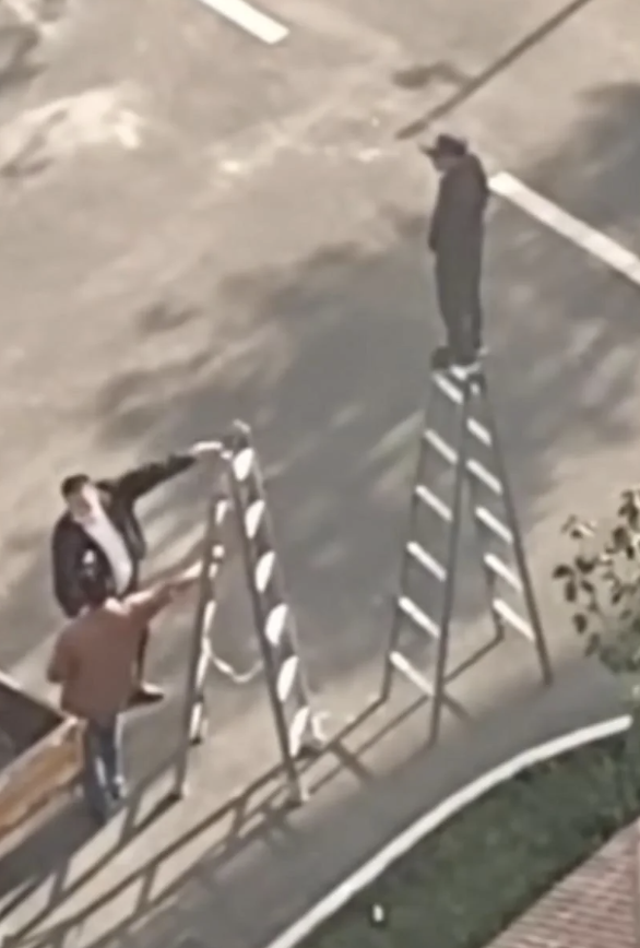 Three people working with two ladders