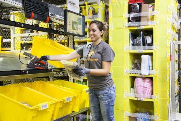 An Amazon fulfillment center employee picking items from bins preparing them for shipment.