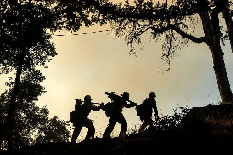 Firefighters walk in line while defending the Mount Wilson observatory during the Bobcat Fire in Los Angeles