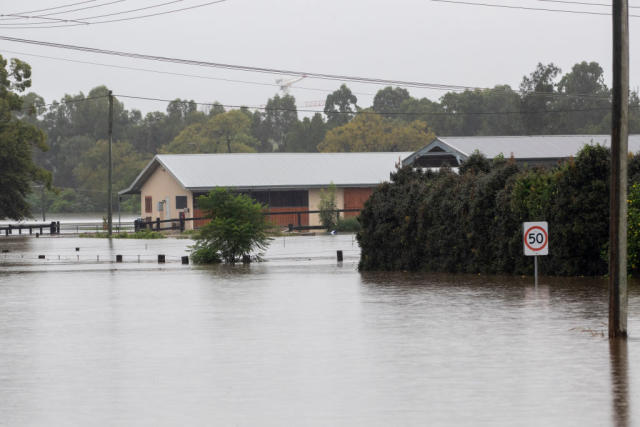 Rising flood waters in Windsor show a house and speed limit sign being engulfed. 