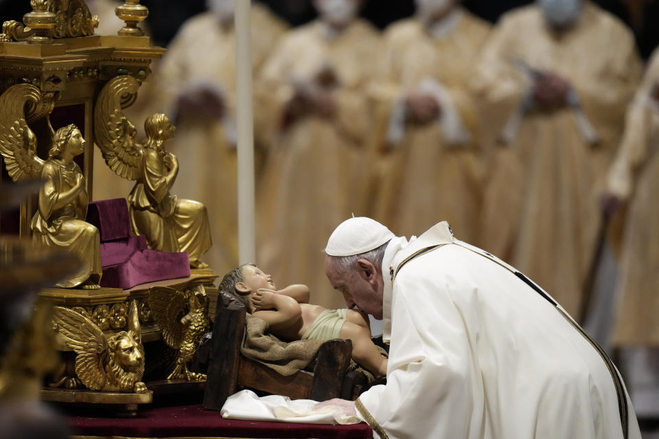 Pope Francis kisses a statue of Baby Jesus as he celebrates Christmas Eve Mass, at St. Peter's Basilica, at the Vatican, Friday Dec. 24, 2021. Pope Francis is celebrating Christmas Eve Mass before an estimated 1,500 people in St. Peter’s Basilica. He's going ahead with the service despite the resurgence in COVID-19 cases that has prompted a new vaccine mandate for Vatican employees. (AP Photo/Alessandra Tarantino)