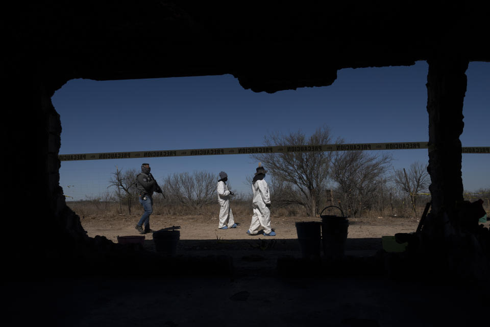 Forensic technicians investigate on a plot of land known as a cartel "extermination site" where burned human remains are buried, on the outskirts of Nuevo Laredo, Mexico, Tuesday, Feb. 8, 2022. After six months of work, there are still more than 30,000 square feet of property to inspect and catalog. (AP Photo/Marco Ugarte)