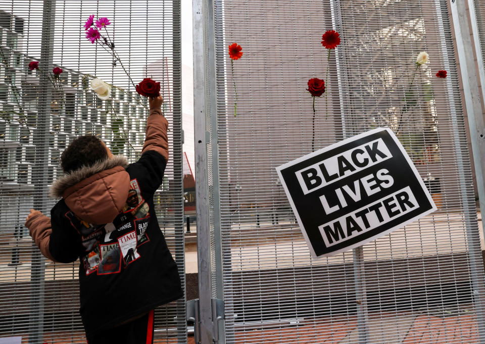 A child places a flower on a fence near a 