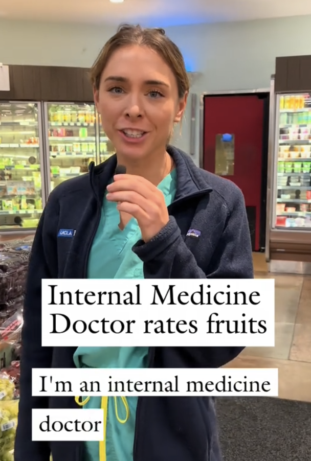 A woman in a medical uniform stands in a grocery store, speaking. Text reads: 