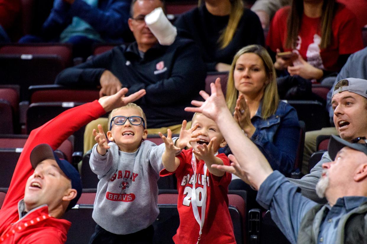 A pair of young Bradley fans, and some older ones, vie for a T-shirt tossed into the crowd by cheerleaders during their game against SIU-Edwardsville on Saturday, Dec. 4, 2021 at Carver Arena.