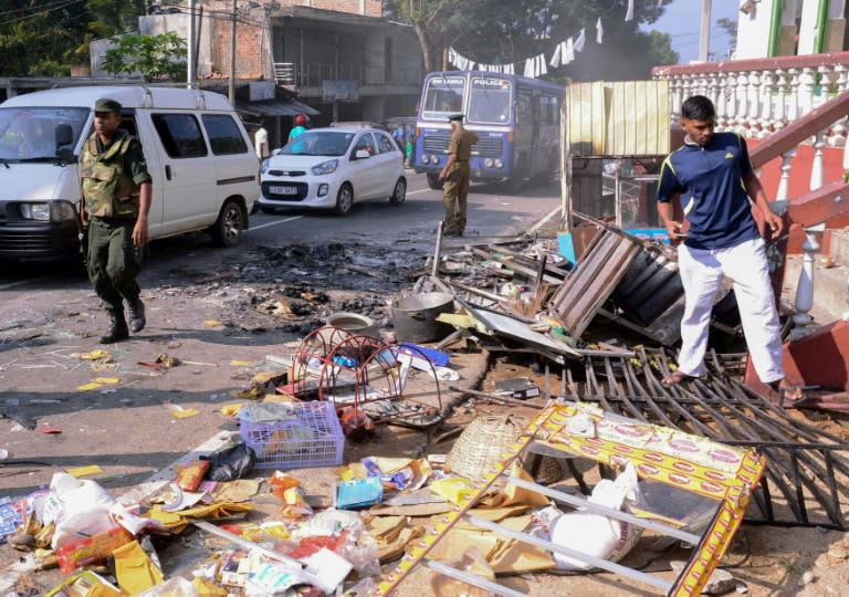 Sri Lankan police commandos patrol next to debris of from a damaged shop in the central district of Kandy on March 6, 2018, after a state of emergency was declared