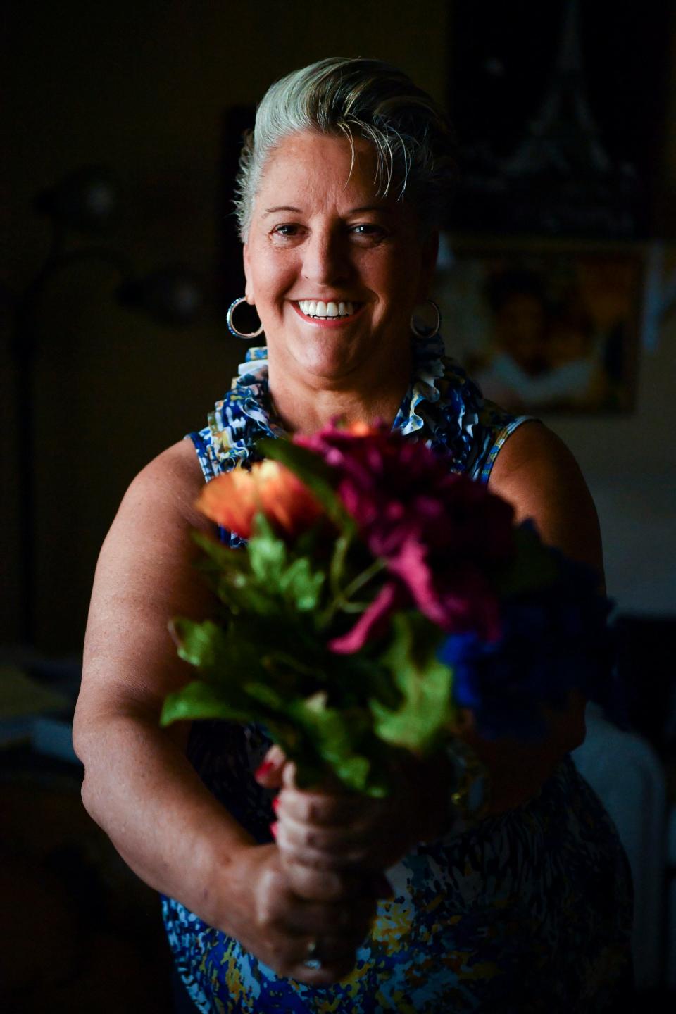 "I love my smile now. I went a year and a half without brushing just because of the depression made it a mountain to conquer," said Yolande Kneuer, who poses for a portrait in her living room, Tuesday, Dec. 6, 2022, in Stuart. Kneuer said she lived as a recluse and in bed for over two years because of her bipolar disorder. She battled through years of depression, a suicidal attempt, homelessness and psychiatric hospitalizations but is now healthy and on the right medications. She recently started a balloon and flower delivery service, A Hug and a Smile.