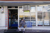 Anthony Milinkovich waits for his turn for a haircut, outside George's Barber Shop on Tuesday, July 14, 2020, in San Pedro, Calif. Gov. Gavin Newsom this week ordered that indoor businesses like salons, barber shops, restaurants, movie theaters, museums and others close due to the spread of COVID-19. (AP Photo/Ashley Landis)