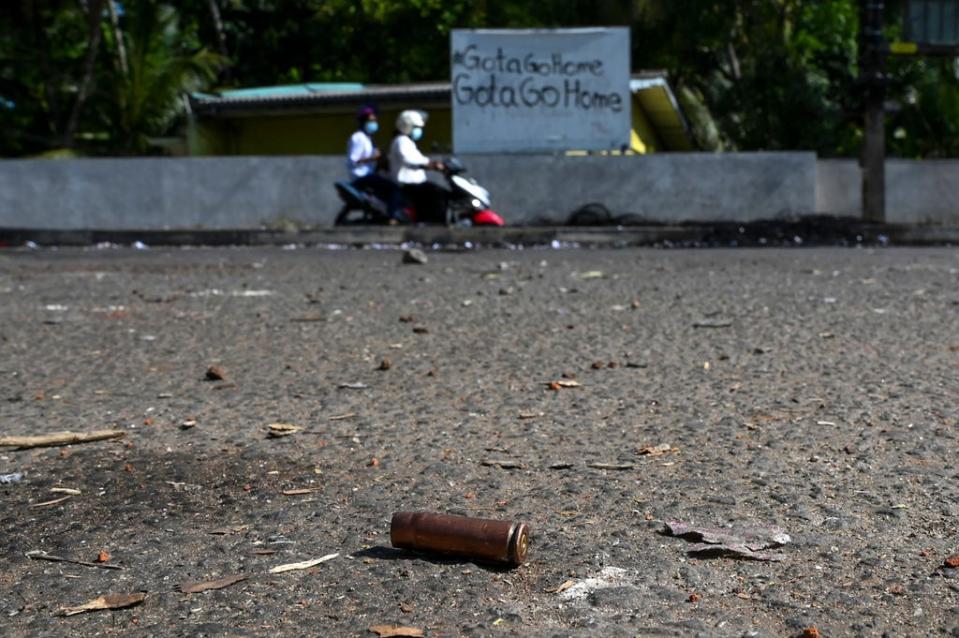 Motorists ride along a street past a spent cartridge in Rambukkana on 20 April, a day after police killed an anti-government demonstrator while dispersing a protest against the high fuel prices (AFP via Getty)