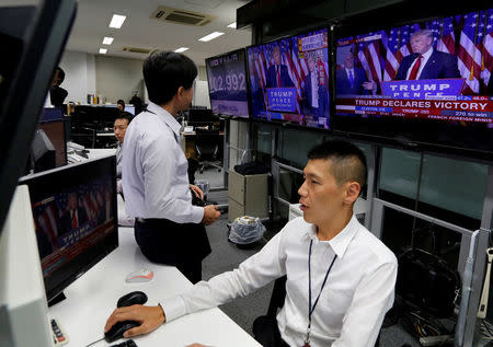 Employees of a foreign exchange trading company look at monitors showing President elect Donald Trump speaking on TV news in Tokyo, Japan. REUTERS/Toru Hanai
