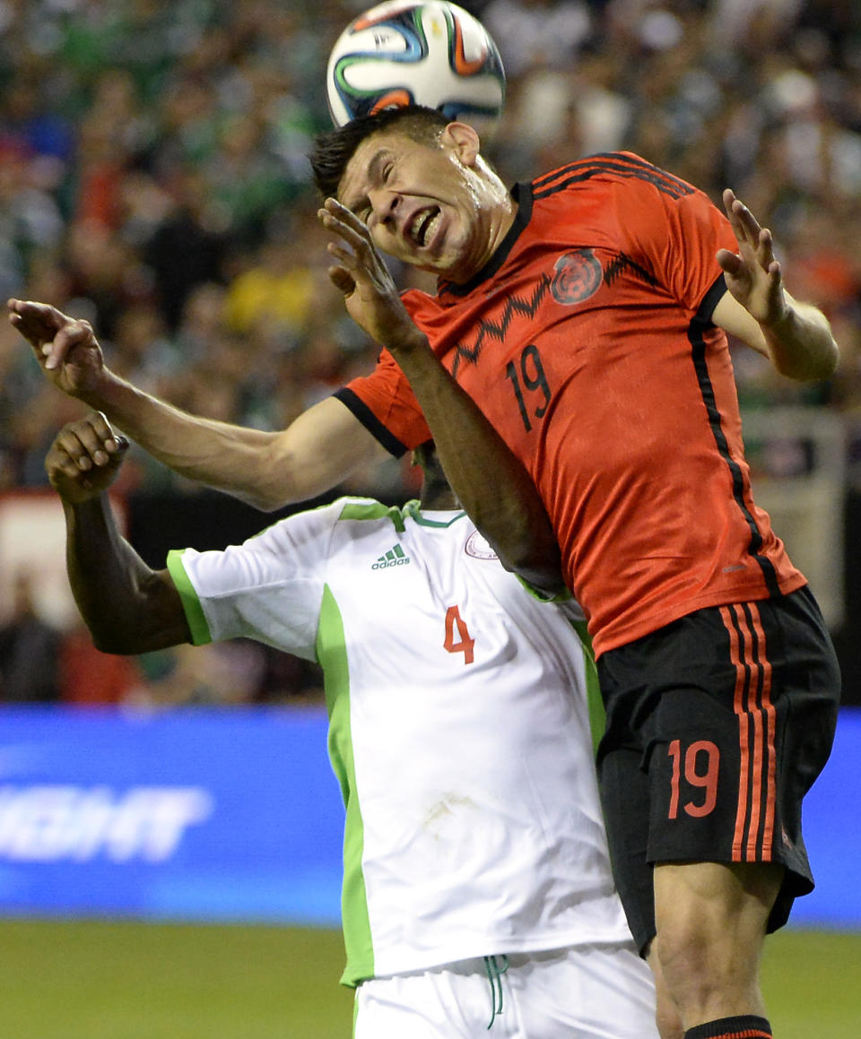 Mexico's Oribe Peralta (19) heads the ball in front of Nigeria's Kenneth Omeruo (4) during the first half of an international friendly soccer match Wednesday, March 5, 2014, in Atlanta. (AP Photo/David Tulis)