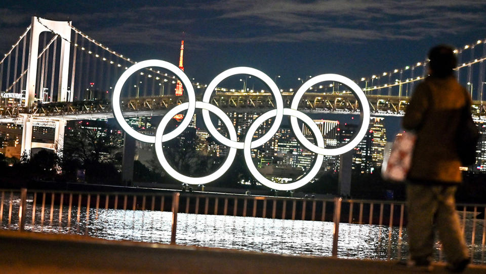 Residents walk past the Olympic rings in Tokyo.