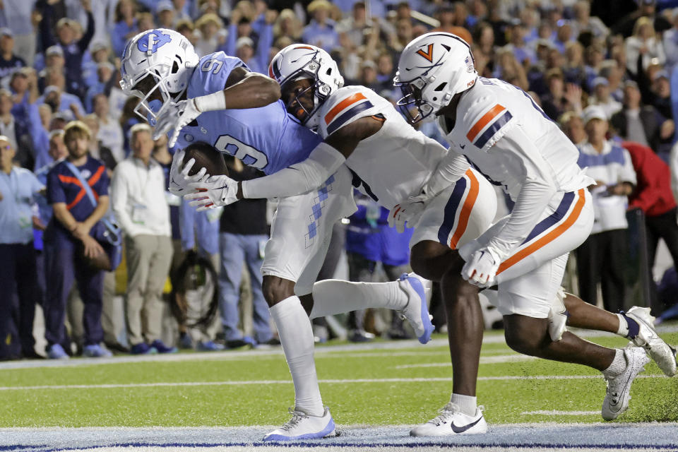 North Carolina wide receiver Devontez Walker (9) pulls in a pass for a touchdown against Virginia safety Coen King, center, and cornerback Dave Herard, right, during the first half of an NCAA college football game, Saturday, Oct. 21, 2023, in Chapel Hill, N.C. (AP Photo/Chris Seward)