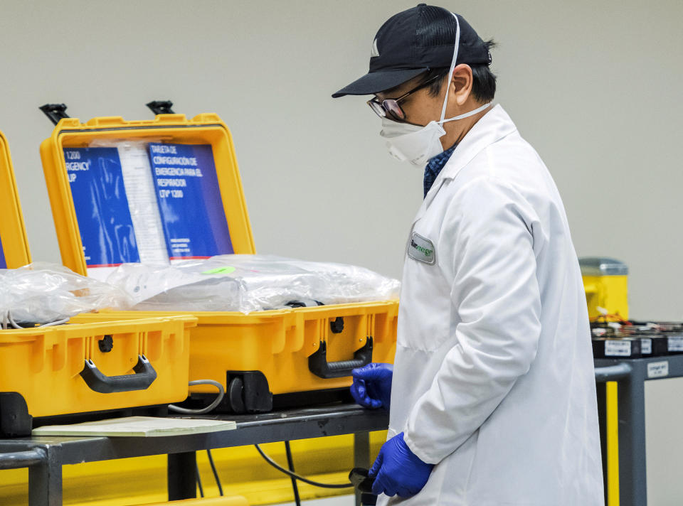 In this Saturday, March 28, 2020, file photo, a staffer works on a ventilator refurbishing assembly line at Bloom Energy in Sunnyvale, Calif. The COVID-19 outbreak has prompted companies large and small to rethink how they do business. Bloom Energy makes hydrogen fuel cells. But recently, they have been refurbishing old ventilators so hospitals can use them to keep coronavirus patients alive. (Beth LaBerge/KQED via AP, Pool, File)