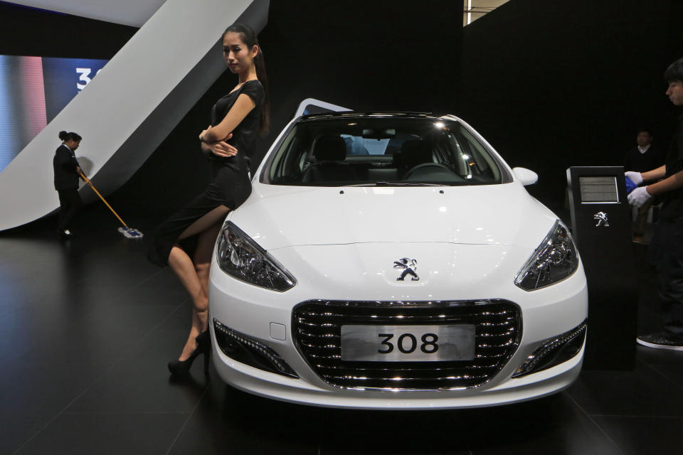 In this Nov. 21, 2013 photo, a model poses by a Peugeot 308 at the company's booth during the Guangzhou 2013 Auto Show in China's southern city of Guangzhou. French automakers Peugeot and Renault are looking belatedly to China to revive their flagging fortunes but picked a tough time to try to expand. France’s biggest auto brand, PSA Peugeot Citroen, in China since the ‘80s without carving out significant market share, said it will be more aggressive after its local partner, Dongfeng Motor Co., in the week of Feb. 16, 2014 agreed to take a 14 percent stake in PSA. (AP Photo/Kin Cheung)