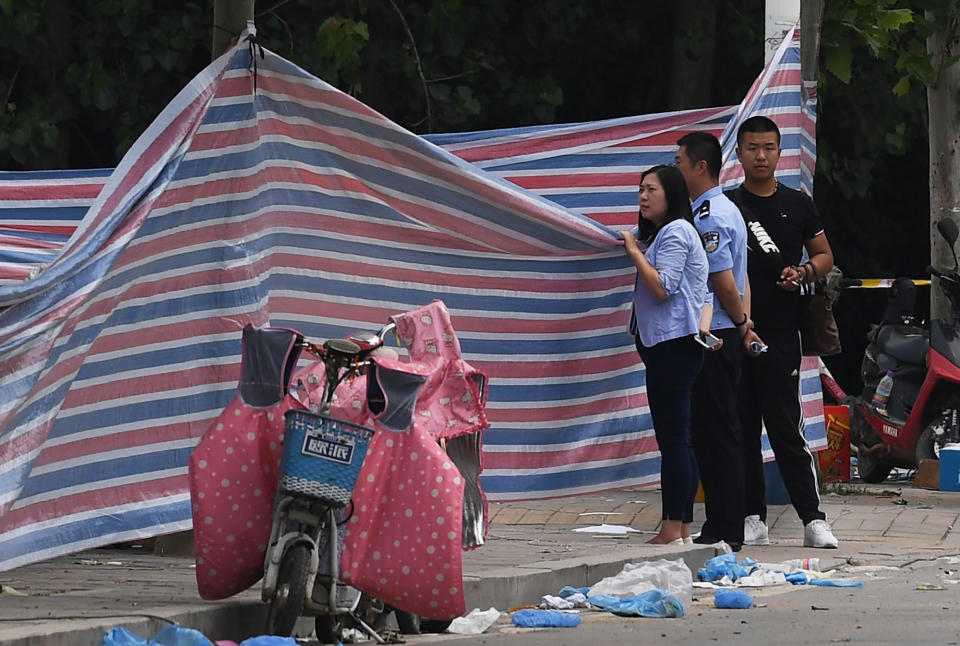 <p>Police officers peer over a screen placed outside a kindergarten where an explosion killed 8 people and injured dozens a day earlier, in Fengxian, in China’s eastern Jiangsu province on June 16, 2017. (Photo: Greg Baker/AFP/Getty Images) </p>