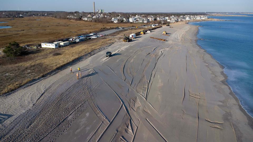 Crews plant beach grass along the newly leveled off dune on Wednesday at Town Neck Beach in Sandwich where dredging material from the Cape Cod Canal has been deposited to nourish and rebuild area.