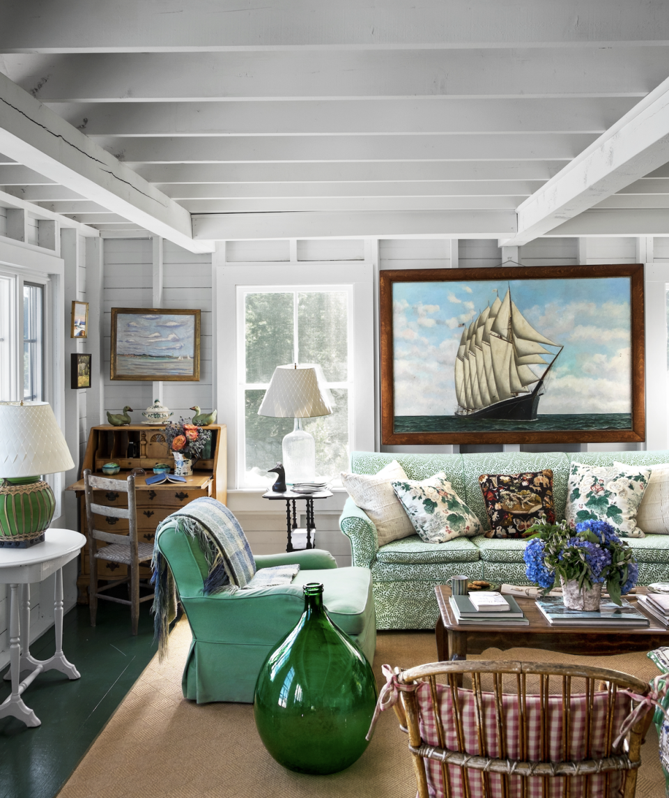 collected maine living room with a green sofa and a giant vintage ship painting on the wall