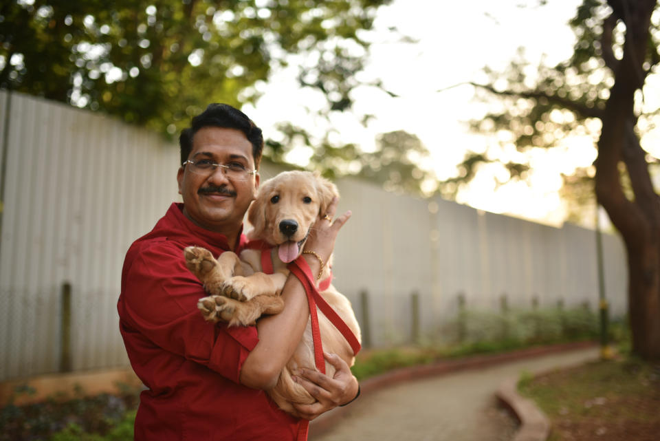 Man standing with his pet dog, a golden retriever puppy