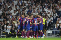 Barcelona players celebrate after their teammate Andreas Christensen, center, scores his side's opening goal during the Spanish La Liga soccer match between Real Madrid and Barcelona at the Santiago Bernabeu stadium in Madrid, Spain, Sunday, April 21, 2024. (AP Photo/Manu Fernandez)