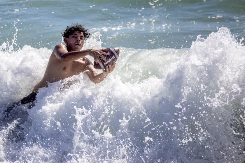 El Segundo, CA - June 20: Andrew Alamos, 15, of Los Angeles, is enjoying catching a football in the surf at El Segundo Beach on Monday, June 20, 2022 in El Segundo, CA. Temperatures across Southern California are expected to be significantly above normal Monday, bringing a noticeably hot end to the last day of spring. Temps will stay high Tuesday, the first day of summer, but should cool off Wednesday and into Thursday as a system from the north moves in bringing more cloud cover and possibly some moisture. (Francine Orr / Los Angeles Times)