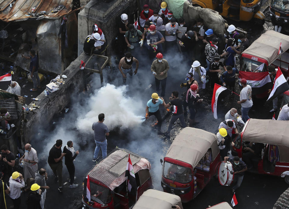 An anti-government protester prepares to throw a tear gas canister fired by Iraq security forces to disperse a during a demonstration, in Baghdad, Iraq, Wednesday, Oct. 30, 2019. (AP Photo/Hadi Mizban)