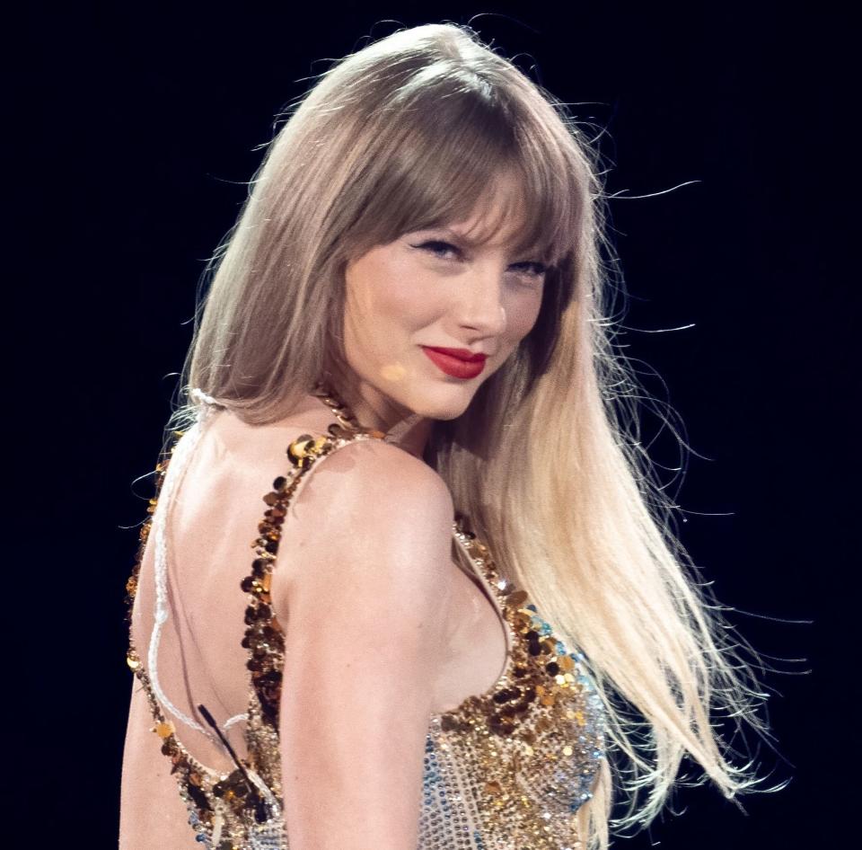 Taylor Swift in a sparkling gold dress performing on stage