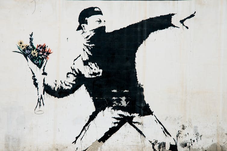 <span class="caption">Banksy’s flower thrower, as painted in the West Bank village of Beit Sahour.</span> <span class="attribution"><a class="link " href="https://www.shutterstock.com/image-photo/beit-sahour-occupied-palestinian-territories-june-336012893?src=SGnIU6YY9PkPKJXVoSTOug-1-0" rel="nofollow noopener" target="_blank" data-ylk="slk:Ryan Rodrick Beiler/Shutterstock;elm:context_link;itc:0;sec:content-canvas">Ryan Rodrick Beiler/Shutterstock</a></span>