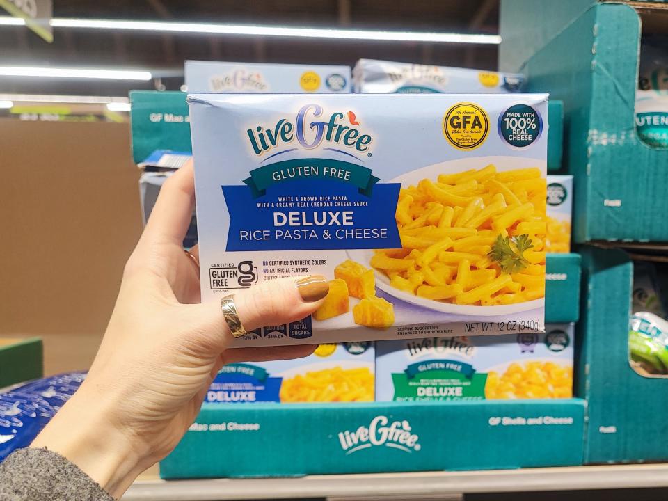 A hand holding a box of liveGfree gluten-free rice pasta and cheese.