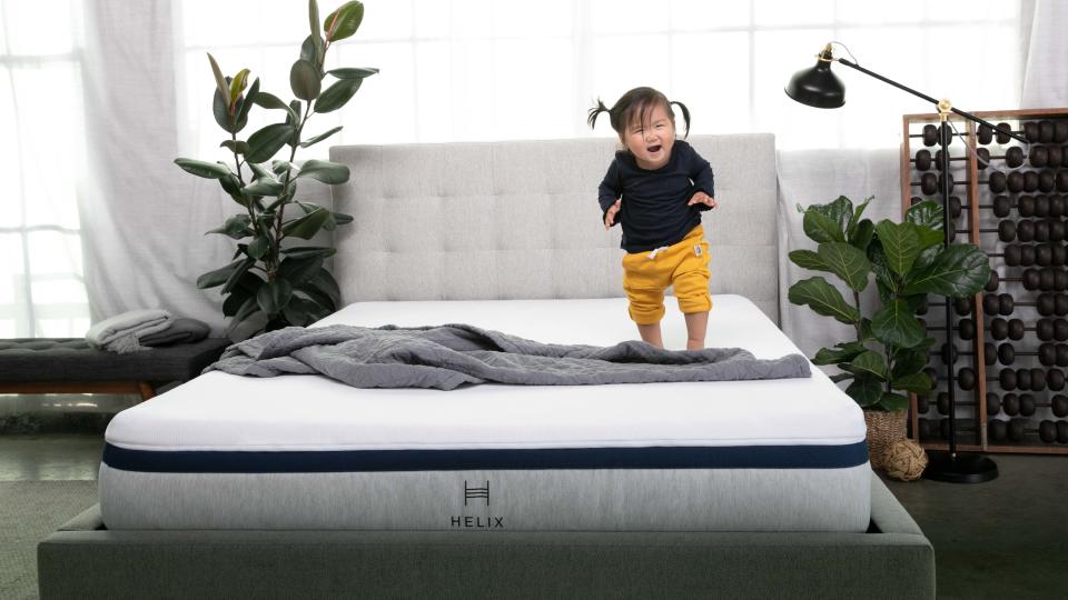 Best mattress: a child with dark hair jumps excitedly on the Helix Midnight mattress