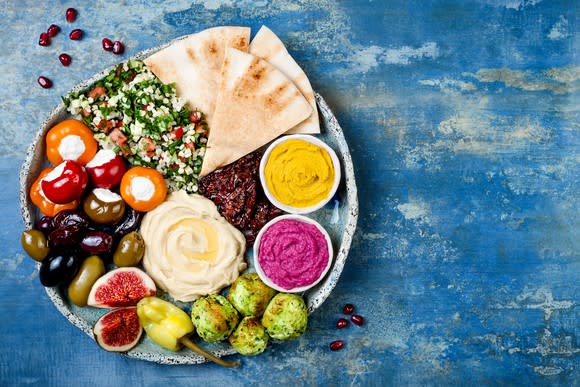 Mediterranean breads, dips, and peppers on a plate.