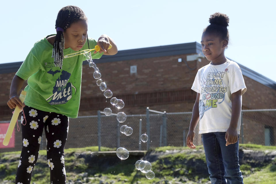 In this photo provided by Charlotte-Mecklenburg Schools, students attending Charlotte-Mecklenburg Schools' summer program blow bubbles at recess, at McAlpine Elementary School, in Charlotte, NC, Thursday June 17, 2021. Dubbed "Camp CMS," the district's programming aims to help students make academic progress and reconnect with their peers for in-person learning in the fall. Like many school districts across the country, the programming is an unprecedented expansion of summer opportunities powered by an infusion of federal and philanthropic funding. (Nancy Pierce/Charlotte-Mecklenburg Schools via AP)