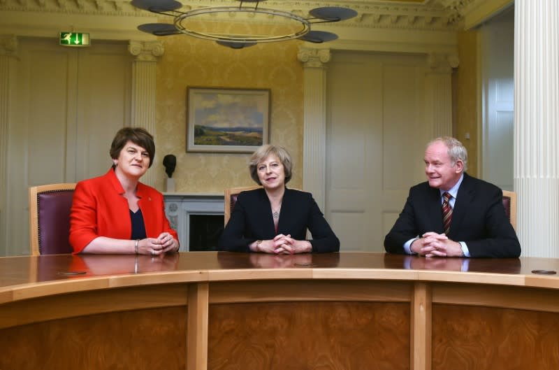 Theresa May entourée de la Première ministre nord-irlandaise Arlene Foster et du vice-Premier ministre Martin McGuinness à Belfast. La chef du gouvernement britannique, venue évoquer la signification d'un Brexit pour l'Ulster, ne veut pas rétablir les contrôles à la frontière avec la République d'Irlande. /Photo prise le 25 juillet 2016/REUTERS/Charles McQuillan/Pool