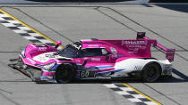 Helio Castroneves drives the Acura DPi over the finish line to win the Rolex 24 hour auto race at Daytona International Speedway, Sunday, Jan. 30, 2022, in Daytona Beach, Fla. (AP Photo/John Raoux)