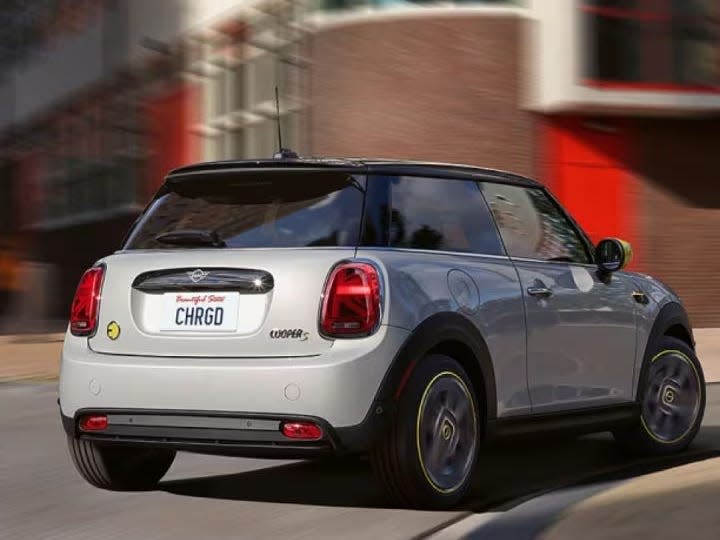 A MINI car drives down a road with a blurred background.