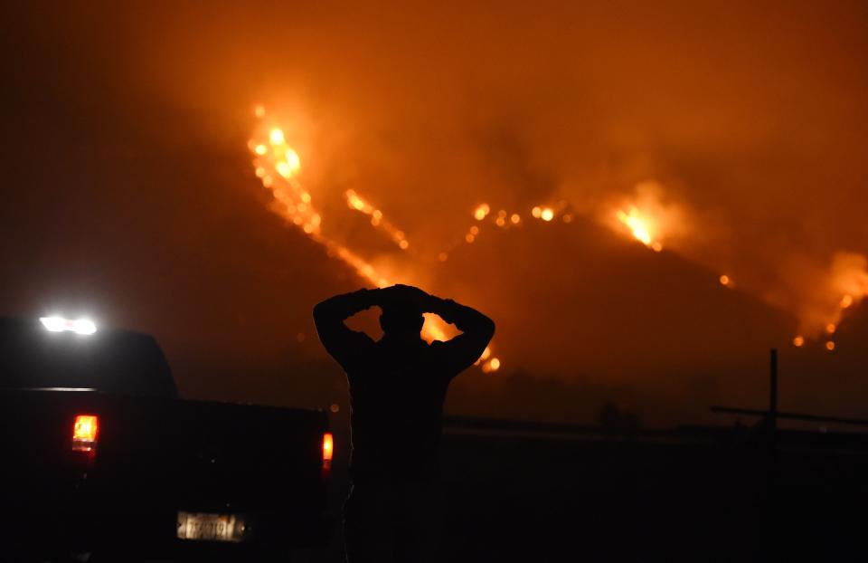 A man watches the Thomas Fire in the hills above Carpinteria, California, December 11, 2017.