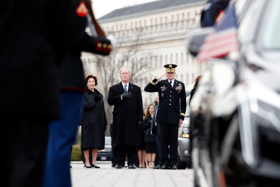 Former President George W. Bush and former first lady Laura Bush put their hands over their hearts as a joint services military honor guard carries the flag-draped casket of former U.S. President George H. W. Bush from the U.S. Capitol to transport it to Washington National Cathedral Dec. 5, 2018 in Washington, DC.