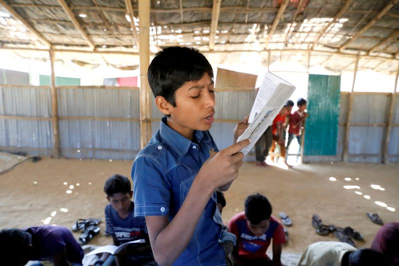 FILE PHOTO: A child reads a book in a makeshift school run by Rohingya teachers in Kutupalong refugee camp in Cox’s Bazar, Bangladesh