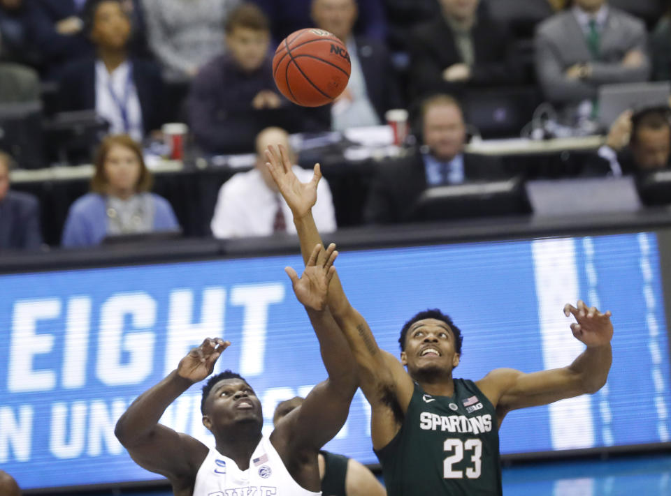 Duke forward Zion Williamson (1) and Michigan State forward Xavier Tillman (23) jump for control of the ball during the opening tip off during the first half of an NCAA men's East Regional final college basketball game in Washington, Sunday, March 31, 2019. (AP Photo}