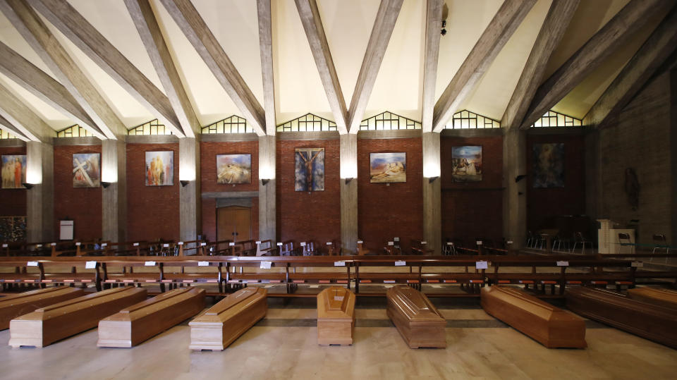 FILE - In this March 26, 2020 file photo, coffins are lined up on the floor in the San Giuseppe church in Seriate, one of the areas worst hit by coronavirus, near Bergamo, Italy, waiting to be taken to a crematory. Italy is seeing a slight stabilizing in its confirmed coronavirus infections two weeks into the world’s most extreme nationwide shutdown, but the virus is taking its silent spread south after having ravaged the health care system in the north. The new coronavirus causes mild or moderate symptoms for most people, but for some, especially older adults and people with existing health problems, it can cause more severe illness or death. (AP Photo/Antonio Calanni, file)