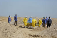 FILE - In this Monday, March 30, 2020 file photo, Iraqi health ministry workers carry a coffin of a person who died from coronavirus at a new cemetery for the people who died from Covid-19 outside the town of Najaf, Iraq. Across the Middle East and parts of South Asia, bereaved families have faced traumatic restrictions on burying their dead amid the pandemic. Religion and customs that require speedy burials in the largely Muslim region have clashed with fears of COVID-19 contagion and government-mandated lockdowns. (AP Photo/Anmar Khalil, File)